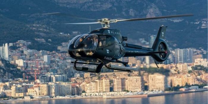 A helicopter flying over the Mediterranean Sea with Monaco in the background